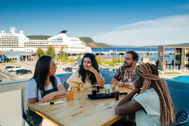 4 personnes, 3 femmes et un homme, discutant à une table au Quai d'escale de La Baie.